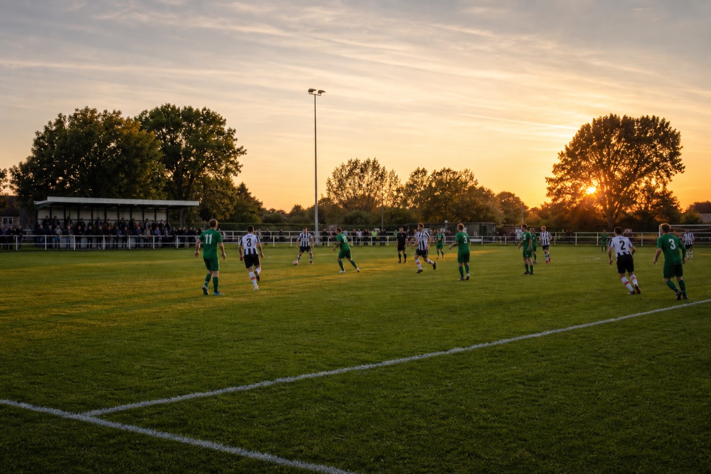 Players contesting a football on a grass pitch at a grassroots club ground